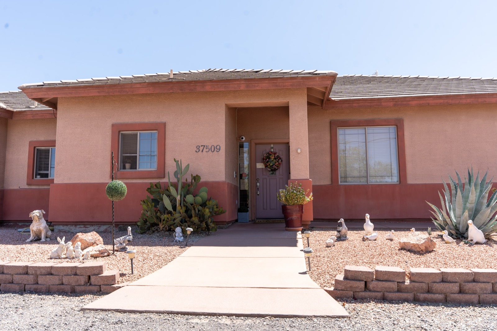 The front entrance of Grace Hill Ranch, a warm terracotta desert home with cactus landscaping